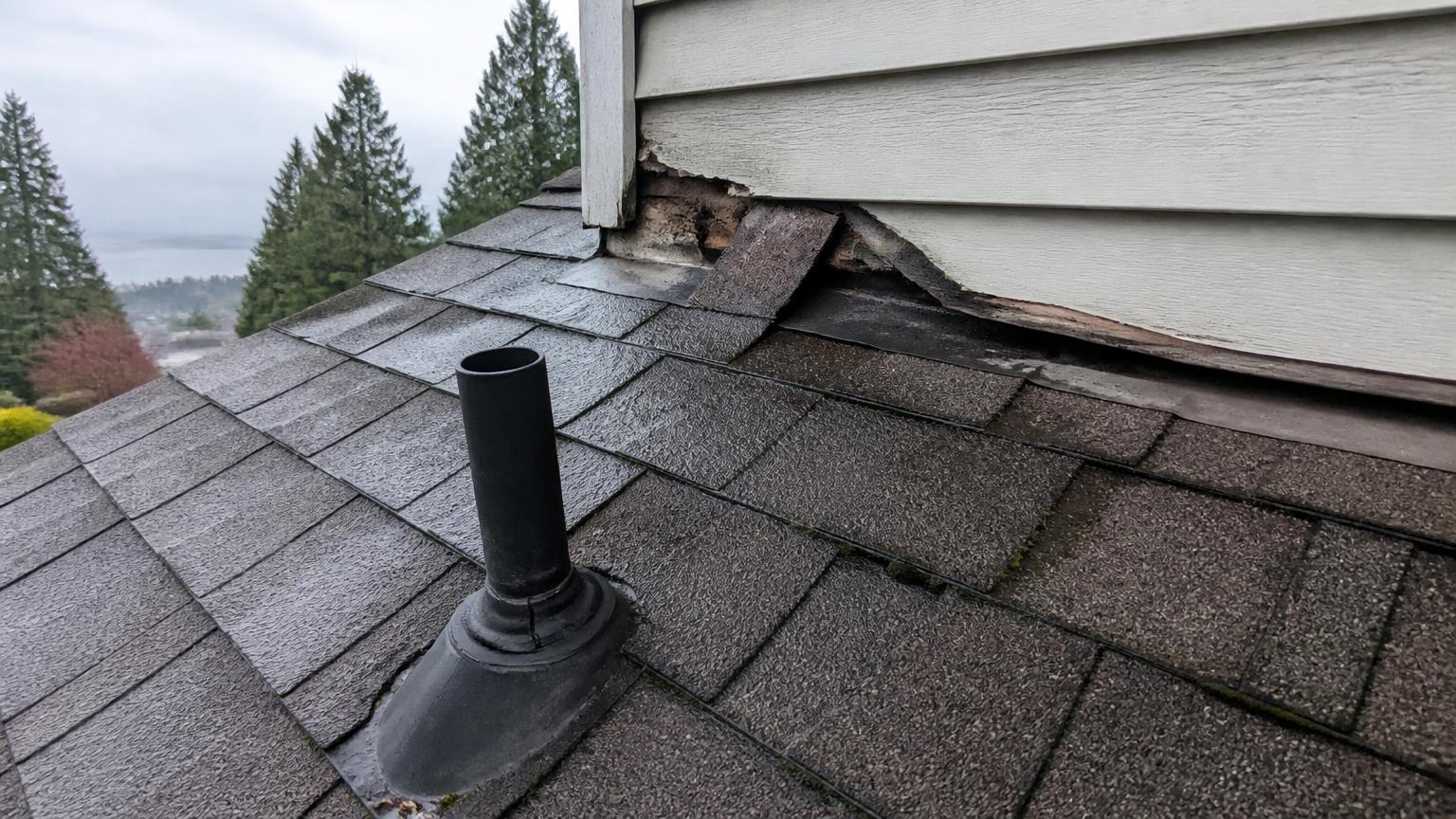 Failed step flashing at a wall-to-roof junction and a cracked vent pipe boot on a damp Surrey asphalt shingle roof