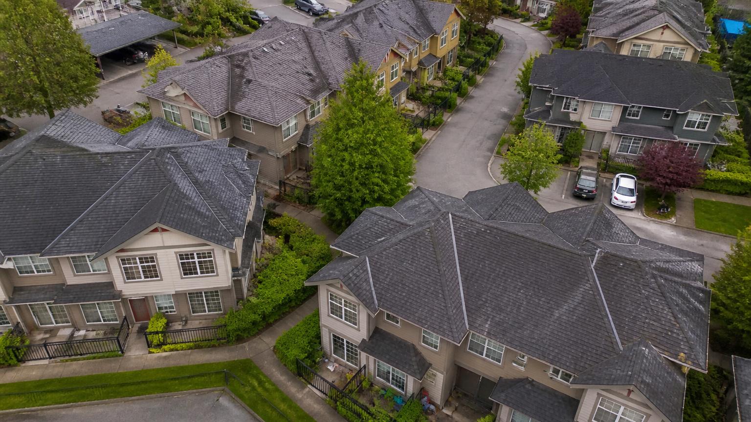 Aerial view of a Lower Mainland townhouse strata complex with asphalt shingle roofs of varying age