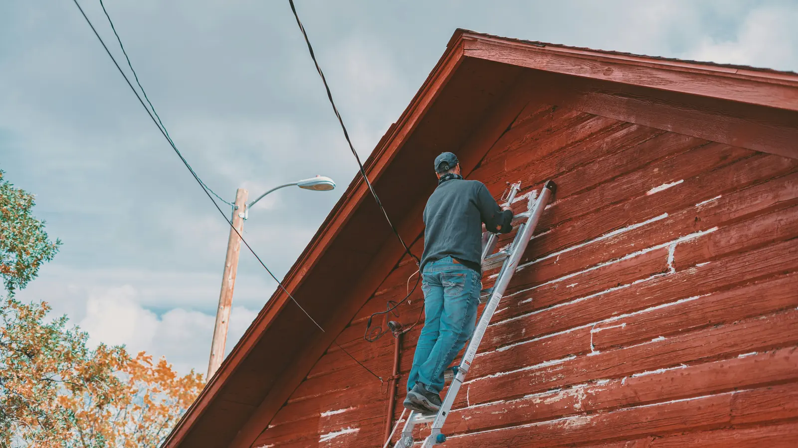 Painter applying an exterior finish from a ladder
